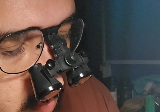 Dr. Theoplistes fazendo o acabamento das peças com lupa